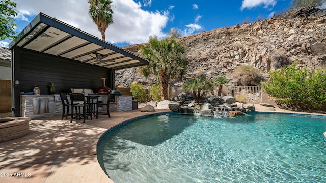 pool featuring a patio, exterior kitchen, fence, and outdoor wet bar