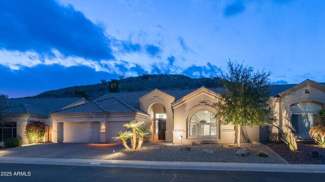 view of front of house with driveway, a garage, a tile roof, a mountain view, and stucco siding