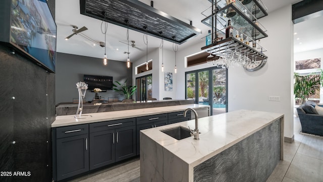 kitchen with light stone counters, french doors, a center island with sink, open floor plan, and a sink