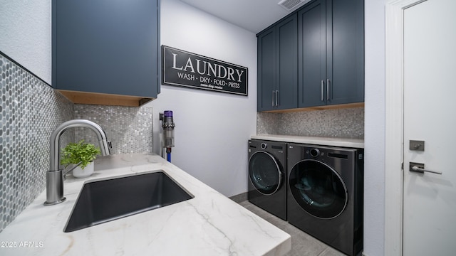 laundry area with a sink, visible vents, washing machine and clothes dryer, and cabinet space