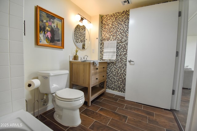 bathroom featuring vanity, toilet, and tile walls