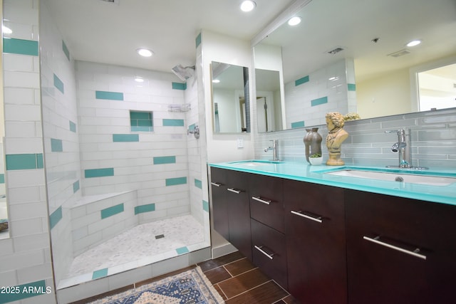 bathroom with tiled shower, decorative backsplash, and vanity