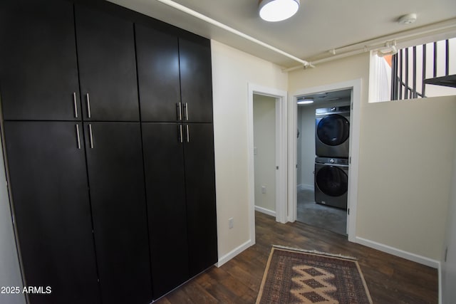 hall featuring stacked washer / drying machine and dark wood-type flooring