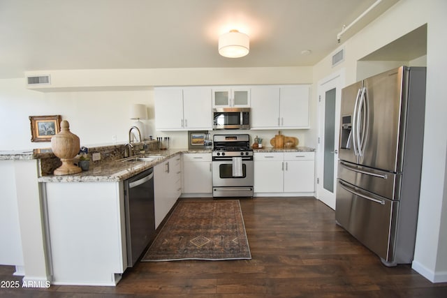 kitchen with kitchen peninsula, light stone counters, white cabinetry, and appliances with stainless steel finishes