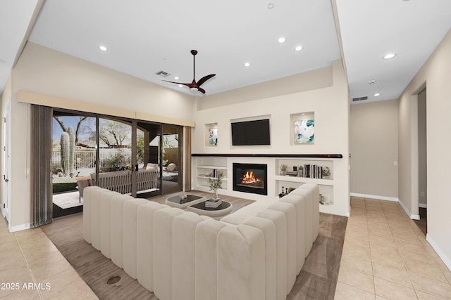 living area featuring a glass covered fireplace, visible vents, recessed lighting, and light tile patterned floors