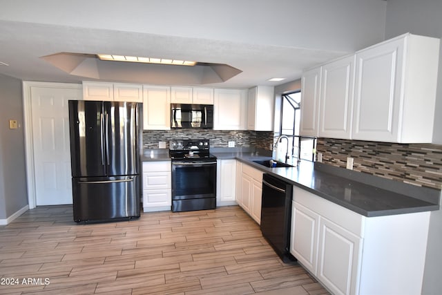 kitchen featuring sink, backsplash, white cabinetry, black appliances, and a raised ceiling