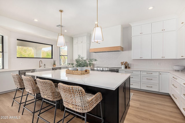 kitchen featuring a kitchen breakfast bar, white cabinetry, a center island, and custom exhaust hood