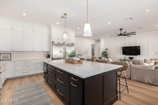 kitchen featuring pendant lighting, built in appliances, white cabinetry, and a kitchen island