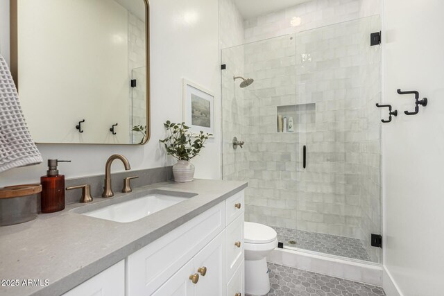 bathroom with tile patterned flooring, vanity, toilet, and a shower with shower door