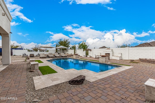 view of pool with an outdoor living space with a fireplace and a patio