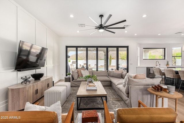 living room featuring hardwood / wood-style floors, ceiling fan, french doors, and sink