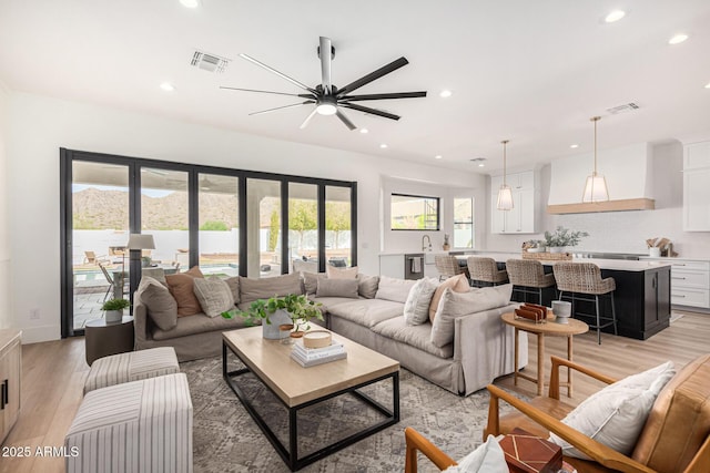 living room with ceiling fan, light wood-type flooring, and a wealth of natural light