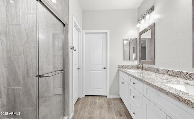 bathroom with hardwood / wood-style flooring, vanity, and a shower with shower door