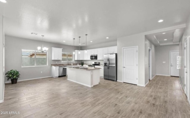 kitchen with a kitchen island, decorative light fixtures, white cabinets, light hardwood / wood-style floors, and stainless steel appliances