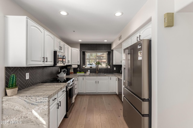 8807 E Dahlia Dr, Scottsdale, AZ 85260 - kitchen featuring tasteful backsplash, light wood-type flooring, white cabinets, stainless steel appliances, and a sink
