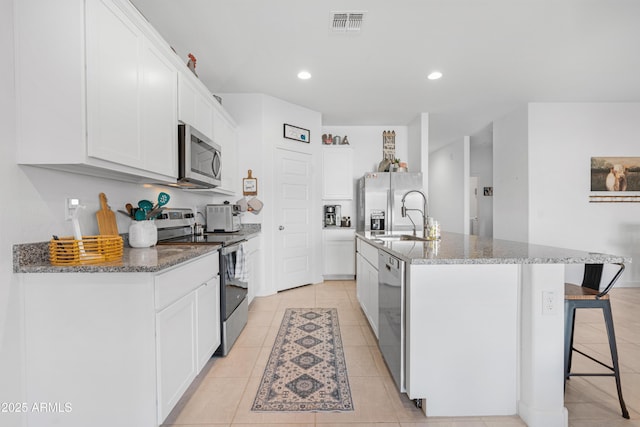 kitchen featuring a kitchen island with sink, white cabinets, and appliances with stainless steel finishes