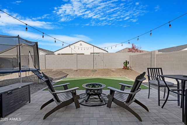 view of patio with a trampoline and an outdoor fire pit