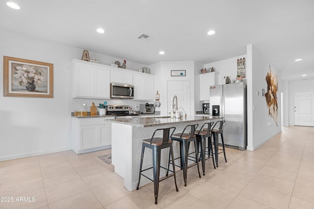 kitchen featuring stone counters, appliances with stainless steel finishes, an island with sink, white cabinetry, and sink