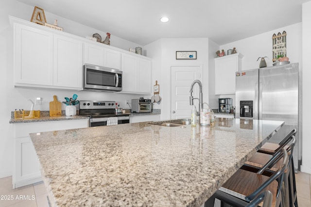 kitchen with a kitchen island with sink, white cabinets, and appliances with stainless steel finishes