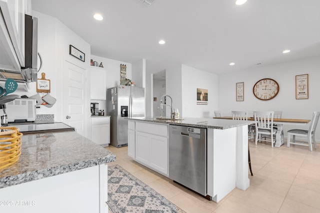 kitchen with sink, light stone counters, a center island with sink, appliances with stainless steel finishes, and white cabinets