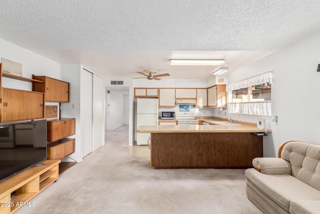 kitchen with a peninsula, white appliances, visible vents, light countertops, and open shelves