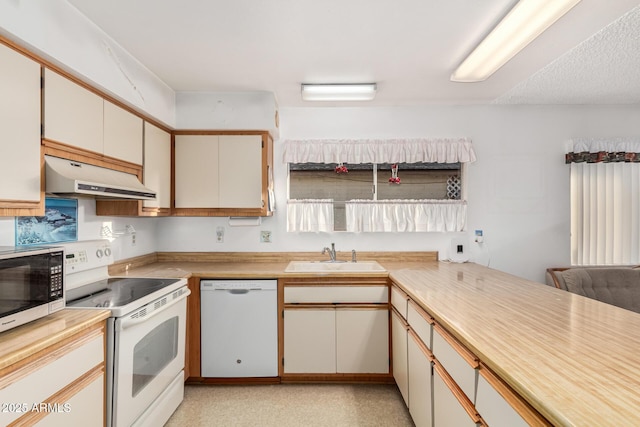 kitchen with a textured ceiling, under cabinet range hood, white appliances, a sink, and light countertops