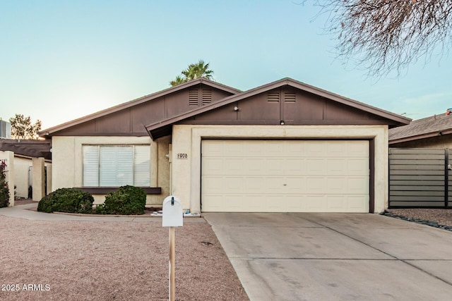 ranch-style house featuring driveway, an attached garage, fence, and stucco siding