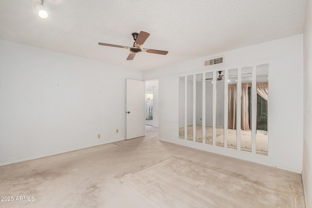 empty room with visible vents, ceiling fan, and a textured ceiling