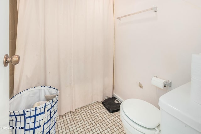 bathroom featuring a shower with shower curtain, toilet, and tile patterned floors