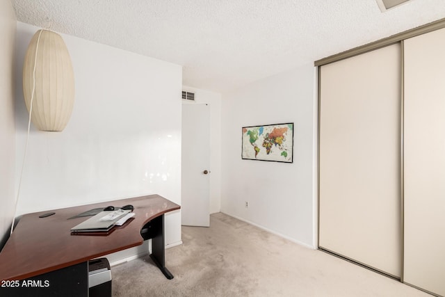 office featuring light carpet, visible vents, and a textured ceiling