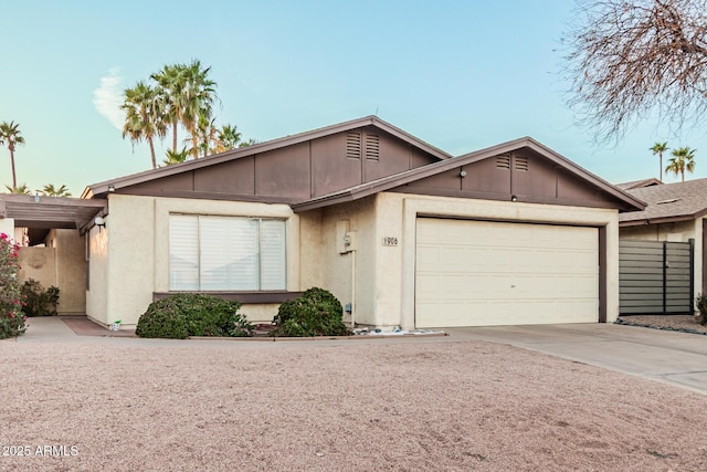 ranch-style house featuring an attached garage, fence, concrete driveway, and stucco siding