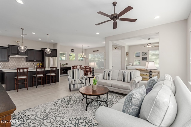 living room featuring ceiling fan with notable chandelier, plenty of natural light, and light tile patterned flooring