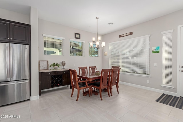 dining area with light tile patterned floors and an inviting chandelier