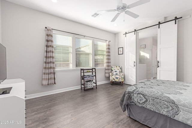 bedroom featuring ceiling fan, a barn door, and dark wood-type flooring