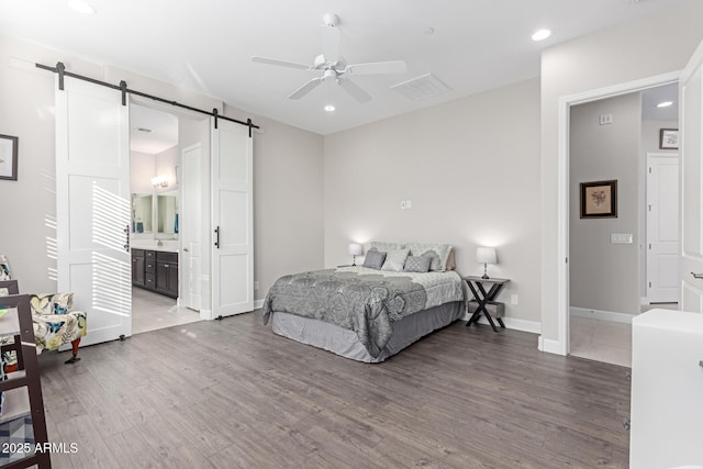 bedroom with ceiling fan, connected bathroom, hardwood / wood-style floors, and a barn door