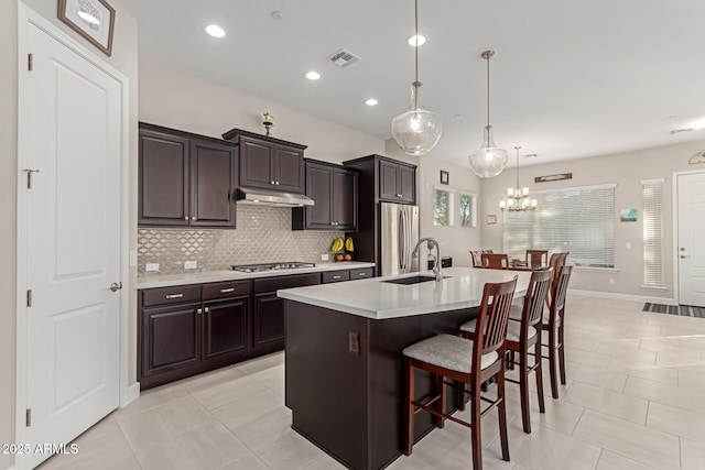 kitchen with stainless steel appliances, a kitchen island with sink, a kitchen breakfast bar, pendant lighting, and sink