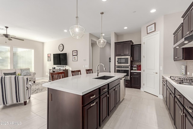 kitchen with ceiling fan, sink, hanging light fixtures, a kitchen island with sink, and stainless steel appliances