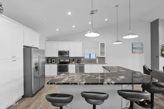 kitchen with a spacious island, decorative backsplash, dark stone countertops, appliances with stainless steel finishes, and white cabinetry