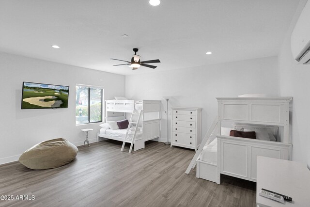 bedroom featuring a wall mounted AC, hardwood / wood-style floors, and ceiling fan