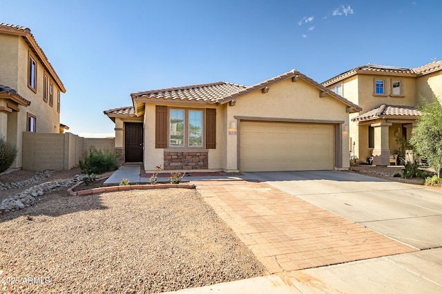 mediterranean / spanish-style home featuring a garage, concrete driveway, stone siding, a tile roof, and stucco siding