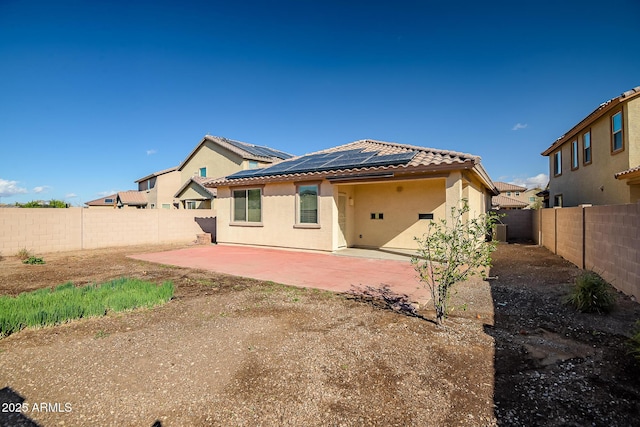 back of property with stucco siding, a fenced backyard, solar panels, and a patio