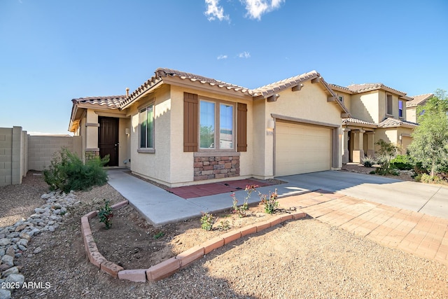 mediterranean / spanish home featuring an attached garage, fence, driveway, stone siding, and stucco siding