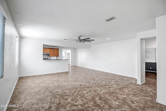 unfurnished living room featuring baseboards, ceiling fan, visible vents, and a wealth of natural light