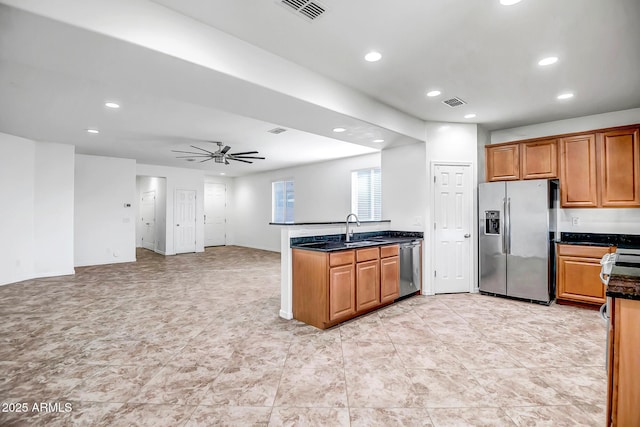 kitchen featuring a peninsula, a sink, a ceiling fan, appliances with stainless steel finishes, and brown cabinetry