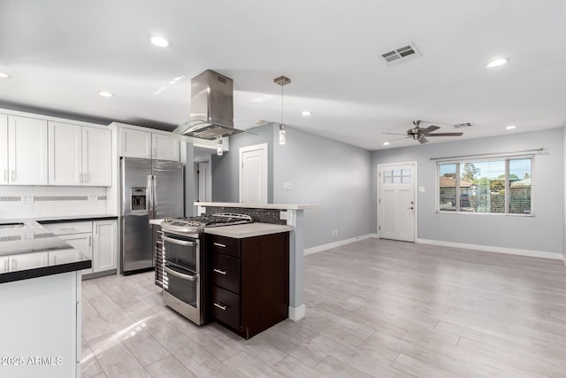 kitchen with appliances with stainless steel finishes, white cabinetry, hanging light fixtures, dark brown cabinets, and island range hood