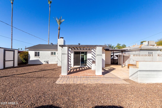 back of property with a storage shed, a pergola, and a patio