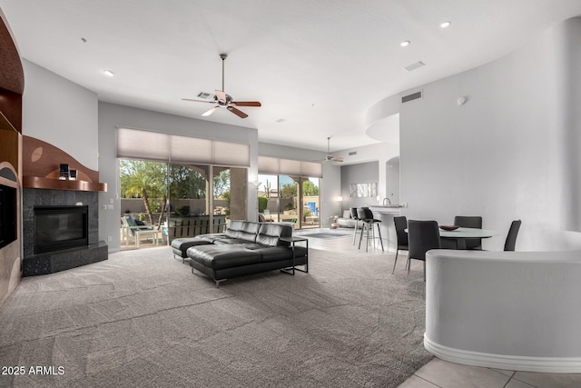 carpeted living room with ceiling fan and a tile fireplace