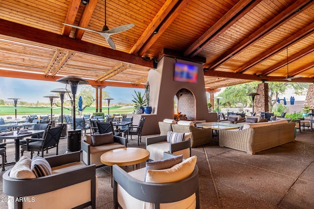 view of patio with ceiling fan and an outdoor living space with a fireplace