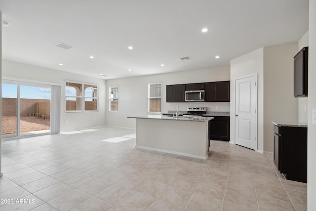 kitchen featuring light stone countertops, light tile patterned floors, appliances with stainless steel finishes, and sink