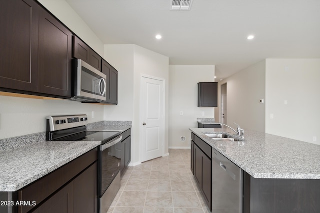 kitchen featuring light tile patterned floors, stainless steel appliances, light stone counters, dark brown cabinetry, and sink